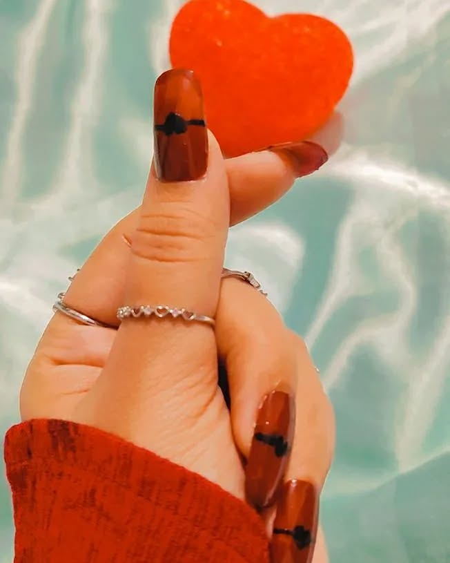 Chocolate brown and cream nails held against a pool