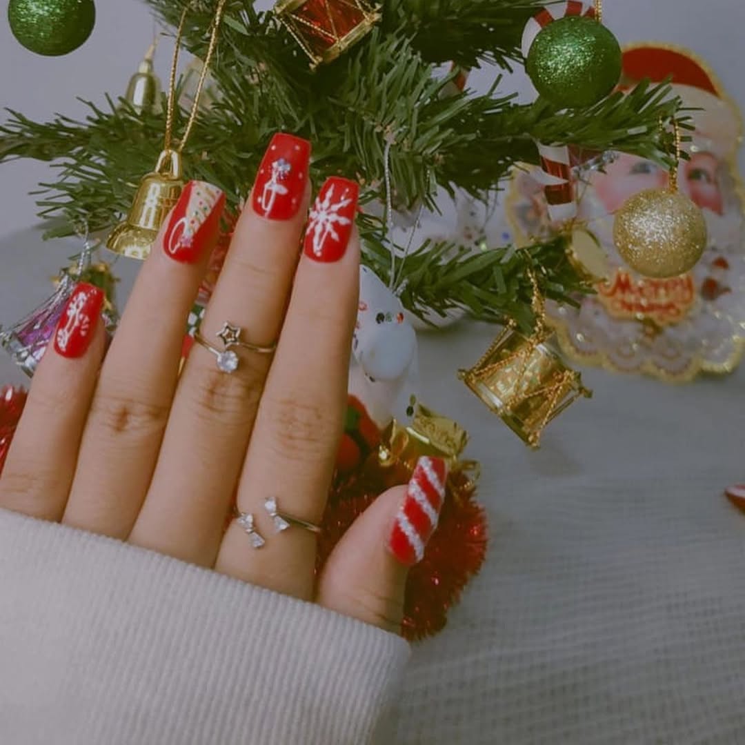 Red festive nail set photographed by a decorated tree